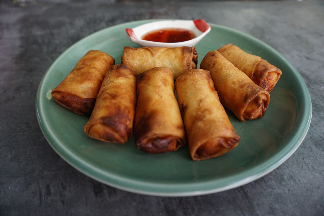 Golden fried spring rolls on a plate with chilli dipping sauce
