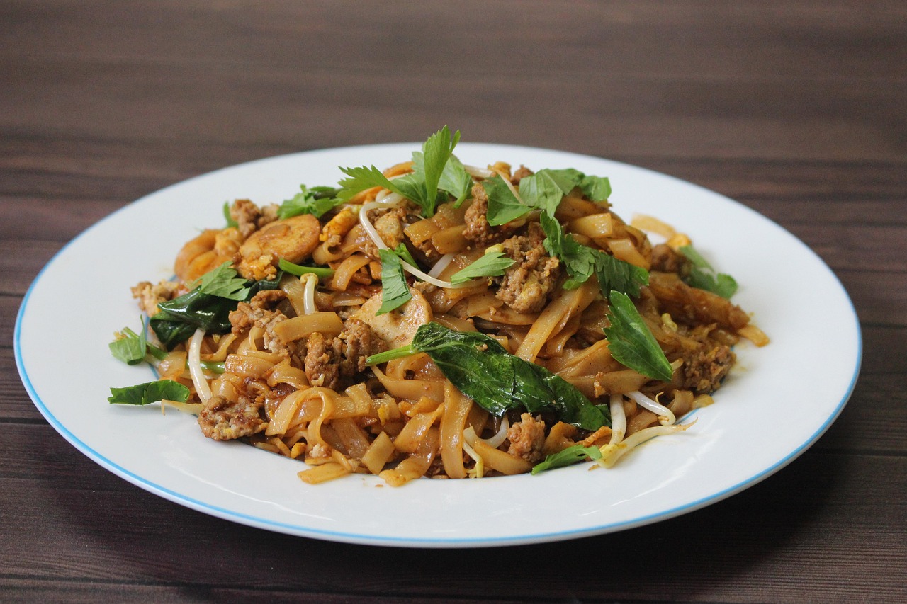 A plate of wok-fried noodles with greens and spring onion