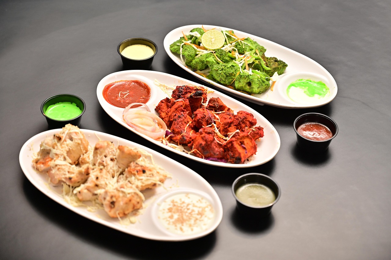 Plates of Indo-Chinese starters with chilli chicken, momos, greens and dipping sauces